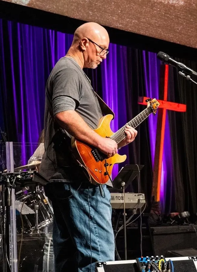 Mike playing an orange electric guitar on stage